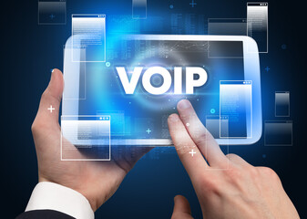 Close-up of a hand holding tablet with VOIP abbreviation, modern technology concept