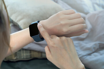 Closeup image of a woman using wireless Smart Watch on sofa