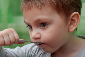 Portrait of a two year old beautiful child. Child eating chocolate cake with a teaspoon
