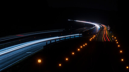 Fototapeta na wymiar Langzeitbelichtung von einer Autobahnbrücke auf die Autobahnbaustelle bei Nacht. Stadtlichter, Sterne auf dem Himmel.