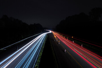 Fototapeta na wymiar Langzeitbelichtung von einer Autobahnbrücke auf die Autobahnbaustelle bei Nacht. Stadtlichter, Sterne auf dem Himmel.