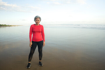 portrait of fit and tired middle aged woman after beach running workout - 40s or 50s attractive...