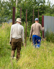 Two workers erect a fence