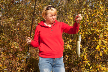 Woman with fishing rod and pike fish autumn