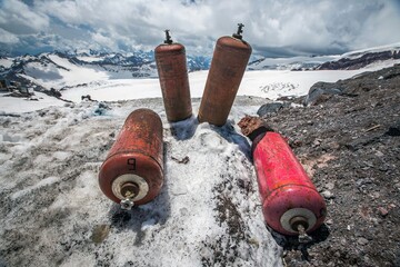 Red cylinders with propane gas on snow in the Caucasus. Clear sunny day. Kabardino-Balkaria, Russia.
