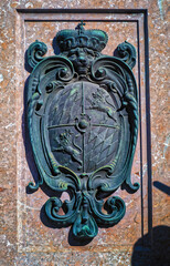 Bronze coat of arms on red marble on the foot of the column of Virgin Mary and Child of Apocalypse at Marienplatz in Munich, Germany.