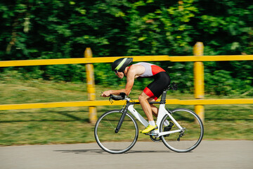 Athlete in low posture riding on a pro bike with streamlined helmet. Side view.
