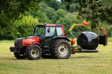 tractor agrícola empaquetando hierba en una bola de plástico ó haciendo bolas de silo