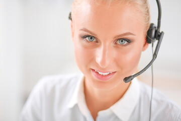 Portrait of pretty young female operator sitting at office desk with headset