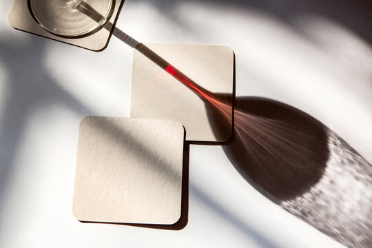 shadow of a glass of red wine with coasters under the sun