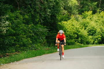 Athletic woman in a professional gear riding on a road with trees on sides
