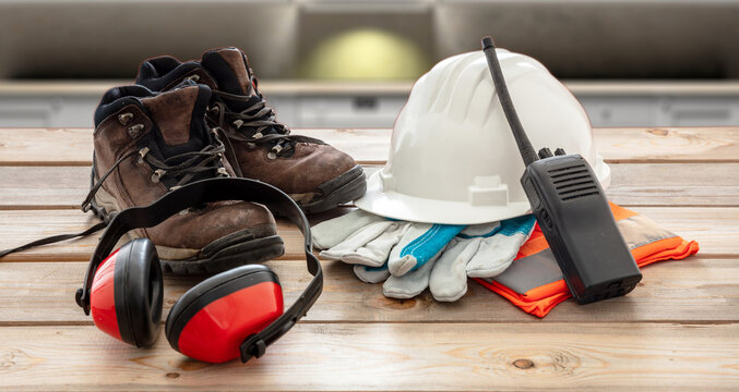 Work safety protection equipment. Industrial protective gear on wooden table, blur construction site background.