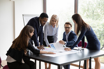 Five diverse focused employees make project research at group meeting. Expressing professional...