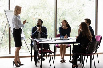 50s old corporate trainer provide knowledge to young professionals company staff multi ethnic people take part at seminar educational meeting sit in boardroom. Workshop flip chart presentation concept