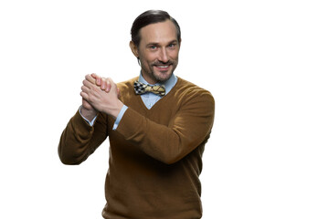 Smiling mature man in sweater is doing a support gesture. Happy european man squeezes his hands. Attractive casual-dressed man isolated on white background.