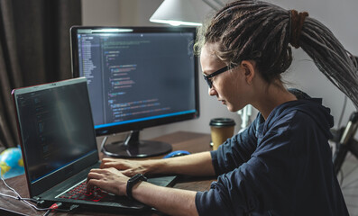 Modern young female programmer is writing program code on a laptop at home. The concept of software development. - obrazy, fototapety, plakaty