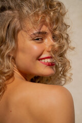 Portrait of a cheerful young woman with red lips and curly hair smiling. 
