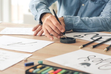 Senior male calligraphist working in office, closeup