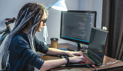 Modern young female programmer is writing program code on a laptop at home. The concept of software...