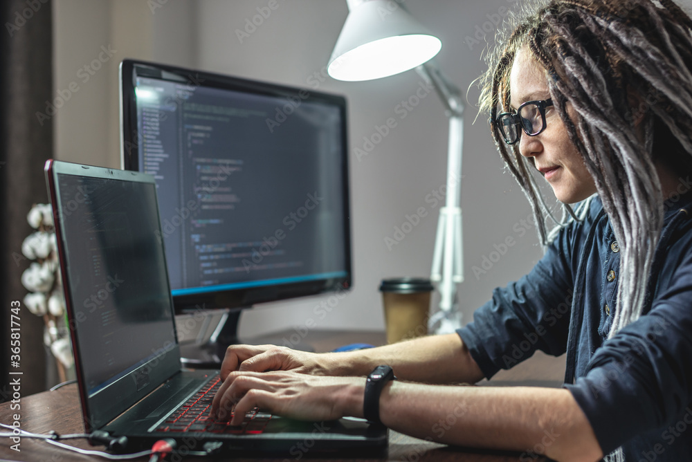 Wall mural modern young female programmer is writing program code on a laptop at home. the concept of software 