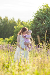 Mother and child laughing and playing in the summer at the lilac and violet lupinus field.