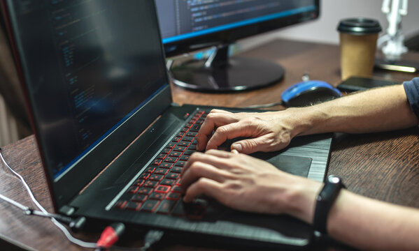 Programmer is writing program code on a laptop at home. Remote work in the IT profession. Software development.