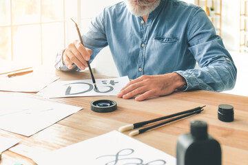 Senior male calligraphist working in office