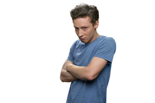 Offended teen boy with folded arms. Portrait of unhappy teen guy is looking angrily. Isolated on white background.