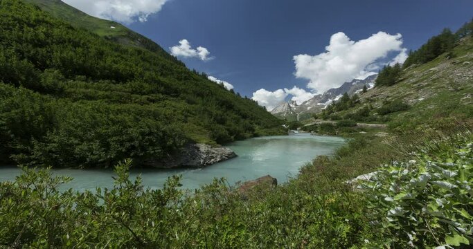 Courmayeur, Val d'Aosta, Alpes of Italy : Dora Veny river and the Pyramides Calcaires on the background, time lapse in a sunny morning.