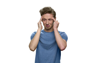 Teenager boy is tired of studying and touching his temples. Portrait of young guy suffering from terrible headache isolated on white.