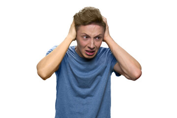 Teen boy is suffering from terrible headache. Pourtrait of young guy touching his head with both hands because of a pain. Isolated on white background.