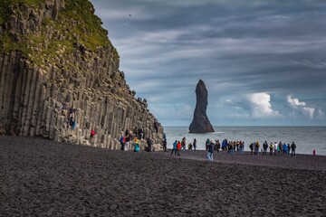 ICELAND, VIK - JULY 25, 2018: Reynisfjara Black Sand Beach and tourists taking photos of basalt...
