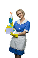 Blonde maid in yellow rubber gloves demonstrating cleaner spray and dusters on white background. Closeup of cleaning rag.