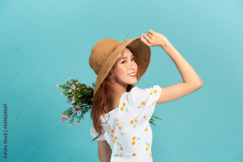 Wall mural Girl in hat and flower dress poses with bouquet.