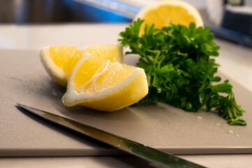 Parsley and freshly cut lemon slices on a cutting board with knife