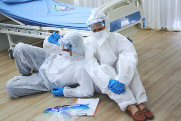 Medical team in Personal Protective Equipment or PPE cloth sitting and so tried after treat patients infected with the Covid 19 virus and treatment in lab of hospital in Thailand