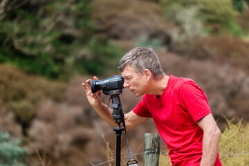Mature man filming with camcorder