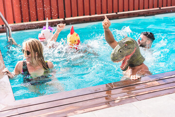 Happy people dancing at pool private party while wearing funny animals masks - Young friends having fun in summer time - Alternative fest during  coronavirus outbreak - Focus on dino face