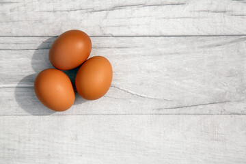 Three eggs on a table top. Directly above with copy space on a rustic table background. 