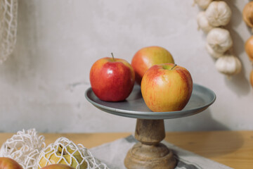 Close up of ripe apples on rustic wood stand over concrete wall in the kitchen.