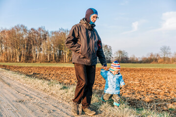Mature man with toddler walking on footpath