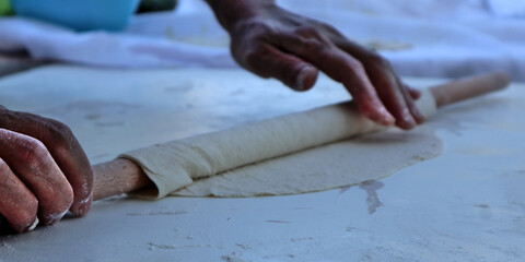 A human hand rolls out the dough