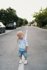Fototapeta premium Portrait of the cute little boy walking on the road in his neighbourhood