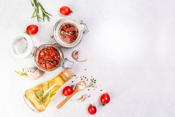Sun dried tomatoes with garlic, oregano, olive oil in a jar on a light table, banner, menu recipe place for text, top view