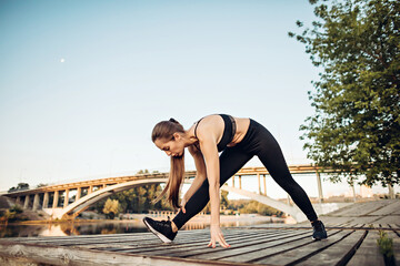 girl do exercise on wooden platform on river coast