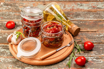 Sun dried tomatoes with fresh herbs and spices in olive oil in a glass jar Food recipe background