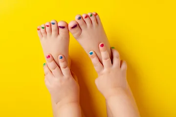 Rolgordijnen Little asian girl with manicure and pedicure on yellow background © Данияр Айбеков