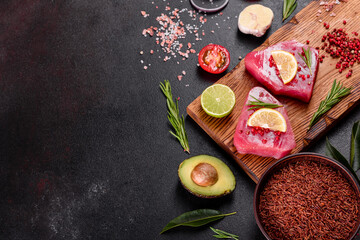 Obraz na płótnie Canvas Fresh tuna fillet steaks with spices and herbs on a black background