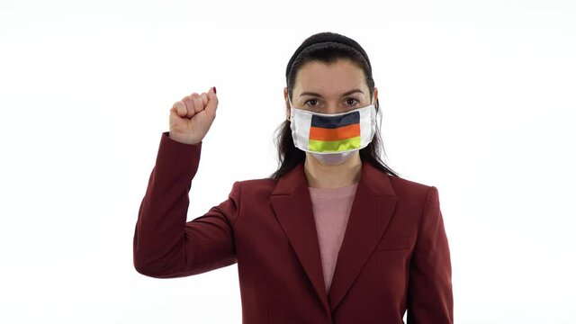 Virus and disease prevention concept. Woman wears a protective medical mask with the image of the flag of Germany. Shows the solidarity with the closed fist hand gesture. Demonstrate solidarity sign.
