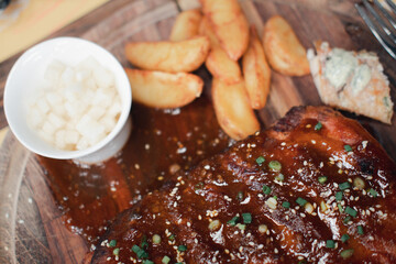 Roasted pork ribs on wooden plate.